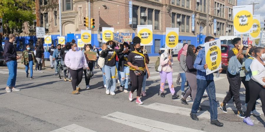 students hold posters and march down a city street