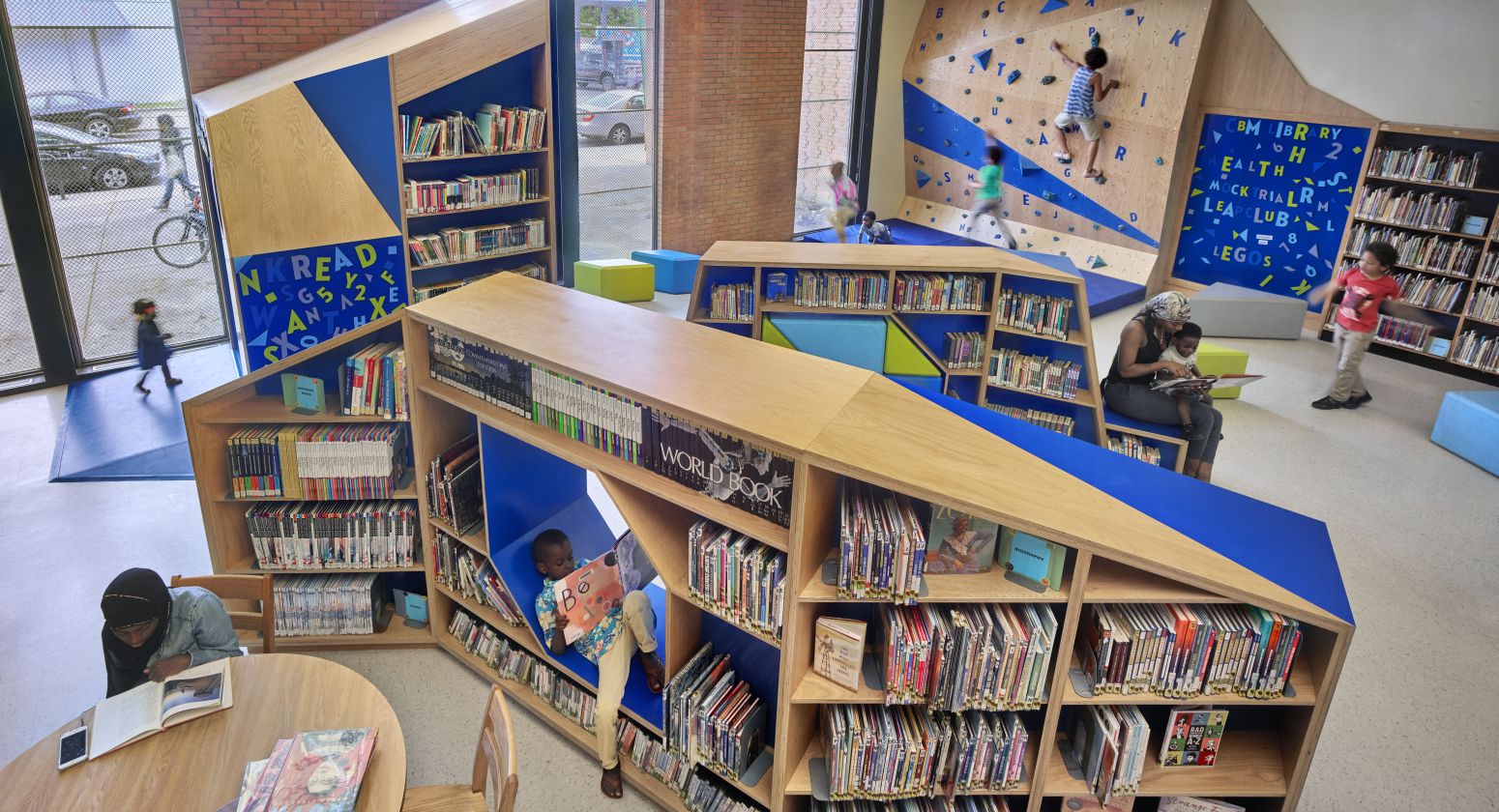 children's section of library featuring book nooks and a climbing wall