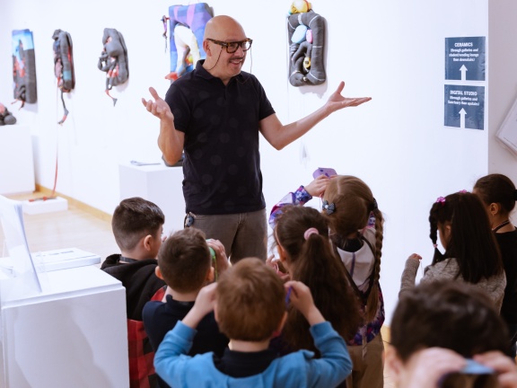 Male arts educator speaking with kindergarteners in gallery space