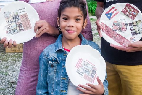 A young girl in a jean jacket holding a decorative plate