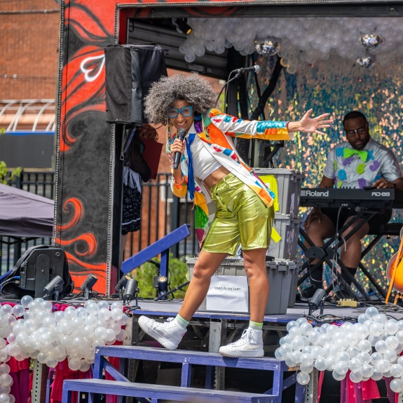Person with big curly hair performing in the foreground of the Beardmobile with a man on the keyboard in the background. Photo Credit: 10th Floor