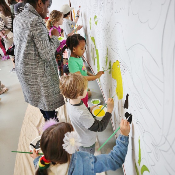 Woman and children painting a mural at Woodmwere Art Museum