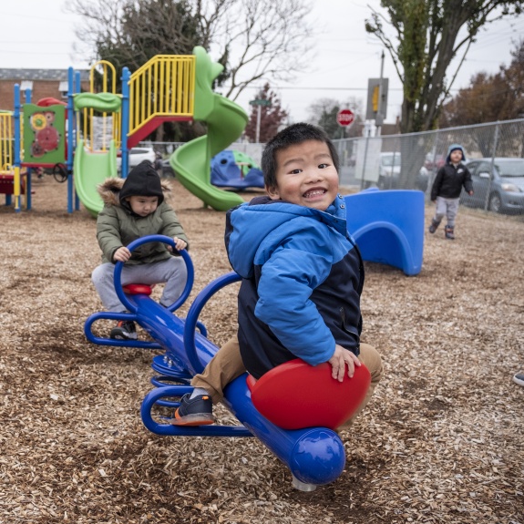 Two little boys on a playground playing on a see-saw.