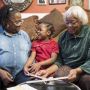 A child sits with her grandmother and home visitor. 