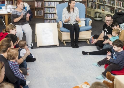 A group of caregivers and infants have a sing along at the local library branch.