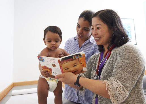 A doctor gives a book to a mother and infant son.